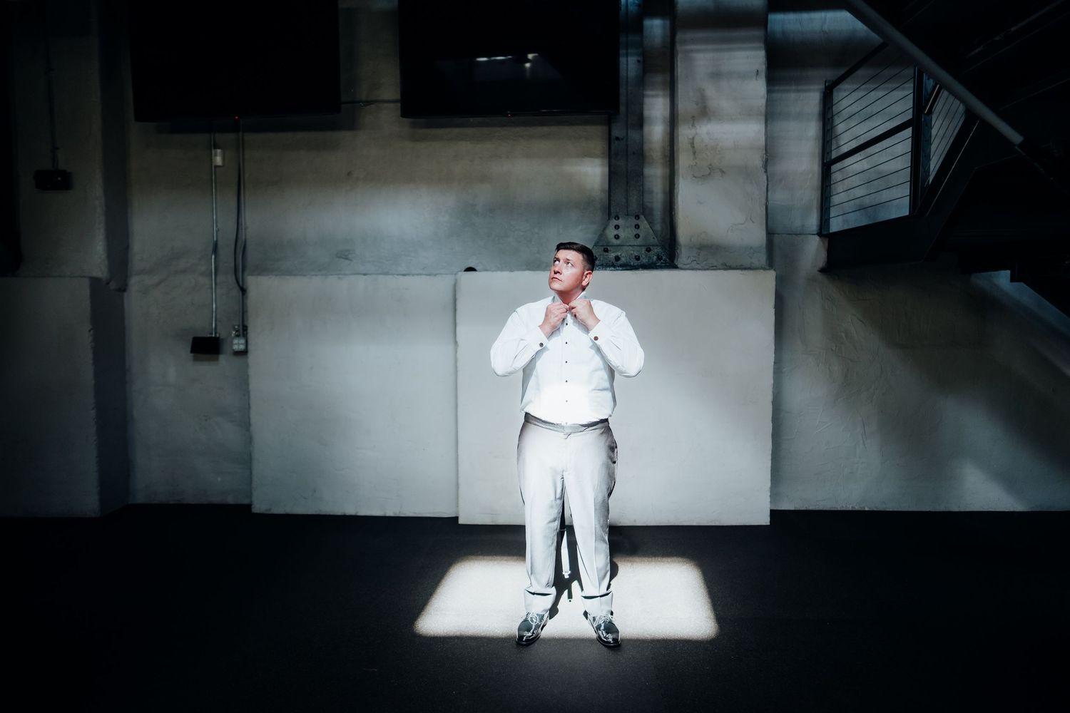 Dramatic spotlit wedding scene in a dark industrial space.