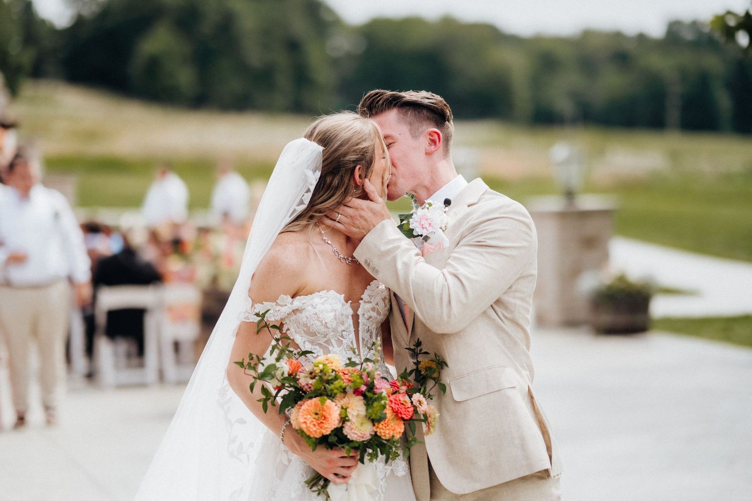 A joyful wedding kiss captured outdoors with a colorful bouquet.