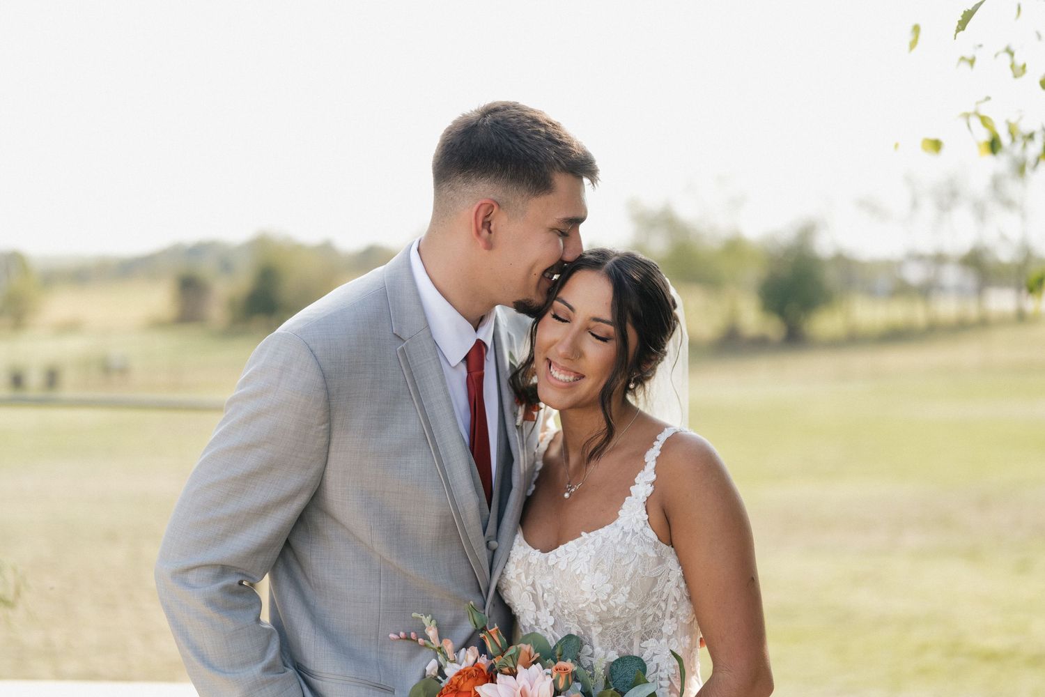 Romantic outdoor wedding portraits with couple in grey suit and white lace gown.