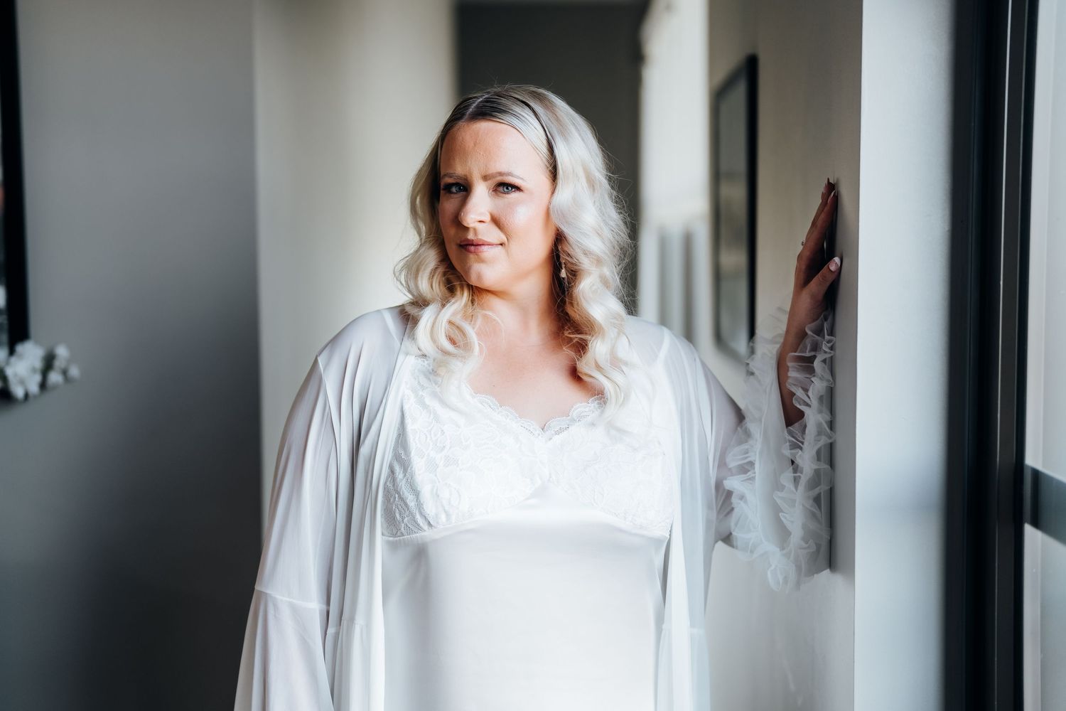 Wedding preparation room with white robes and dresses visible in a well-lit interior space.