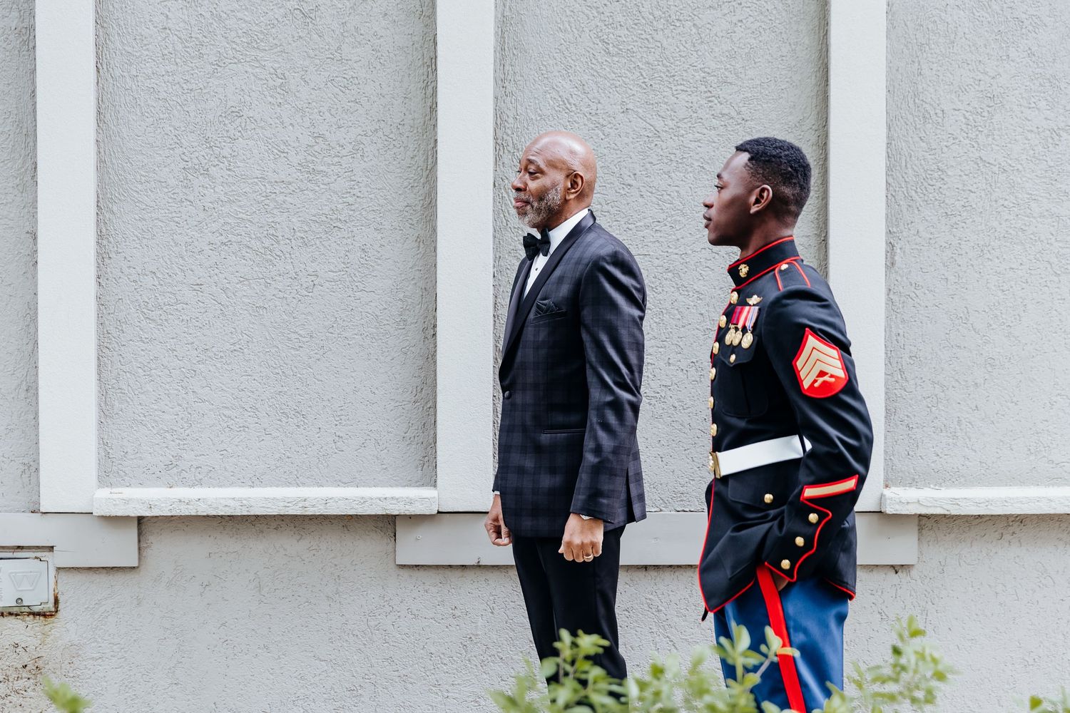 Military service members in dress uniforms stand in formation outside a building.