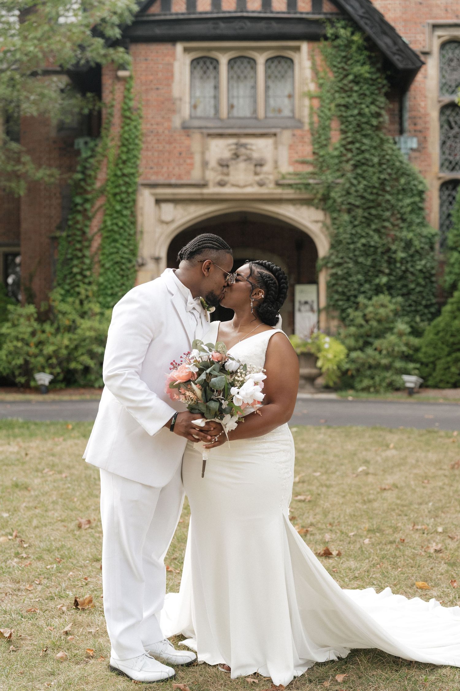 A romantic wedding couple shares an intimate moment in front of a historic brick building with ivy.