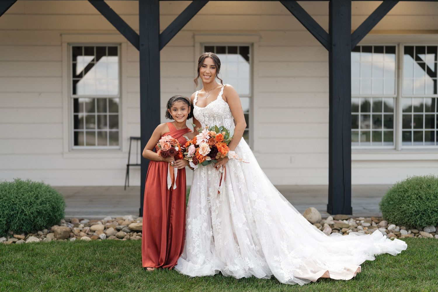 Wedding party members pose in front of a white building with black posts.