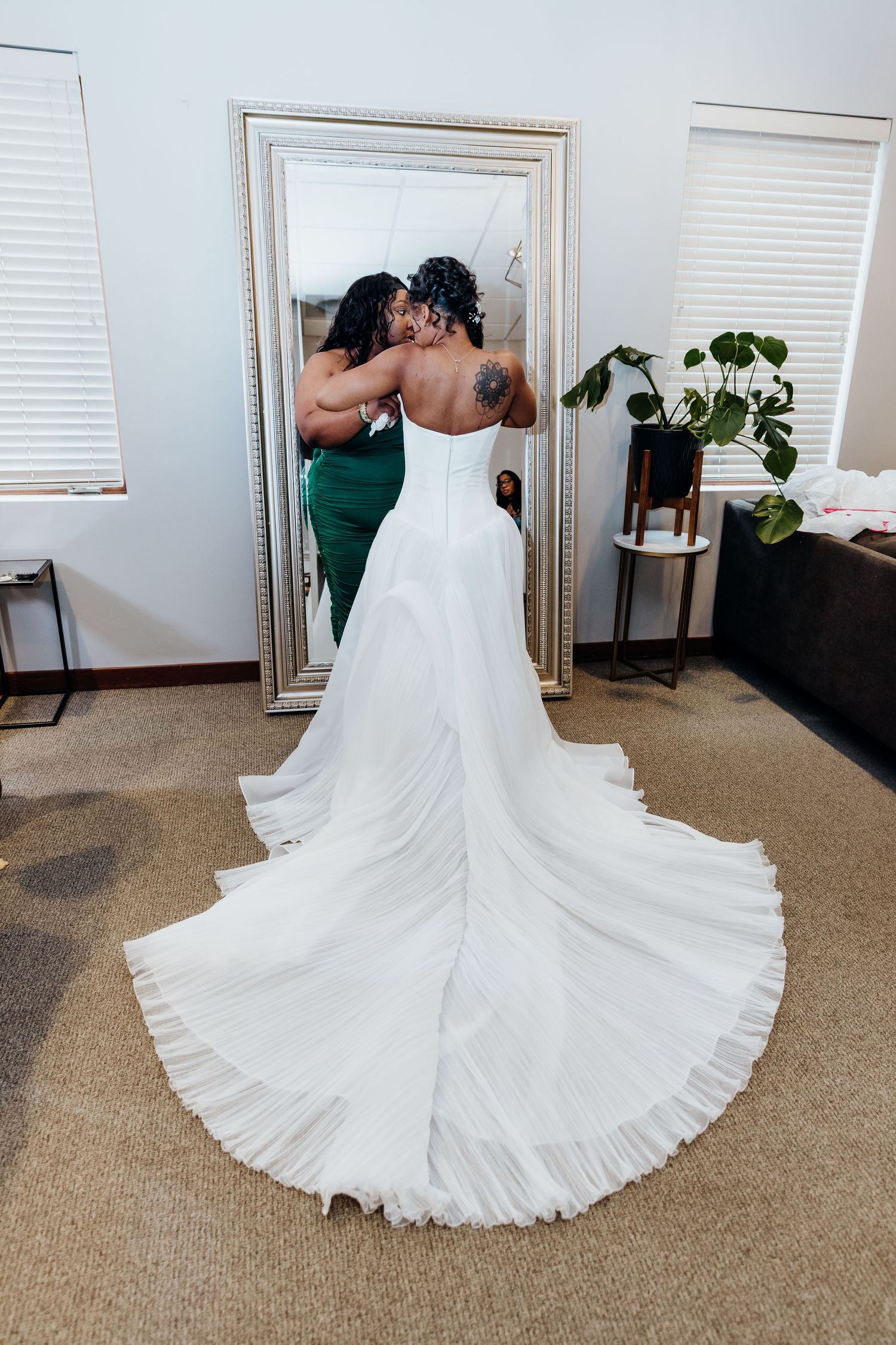 Wedding dress with flowing train spread out beautifully on beige carpet.