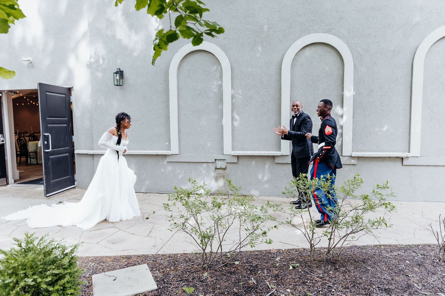 Wedding photography session in progress outside white building with arched windows.