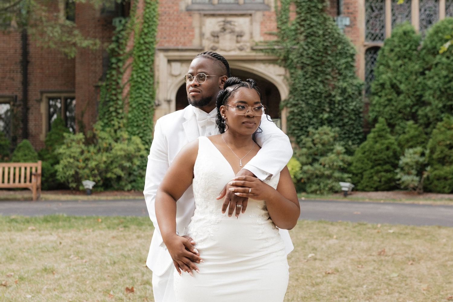 A joyful wedding celebration takes place in front of an ivy-covered brick building on a sunny day.