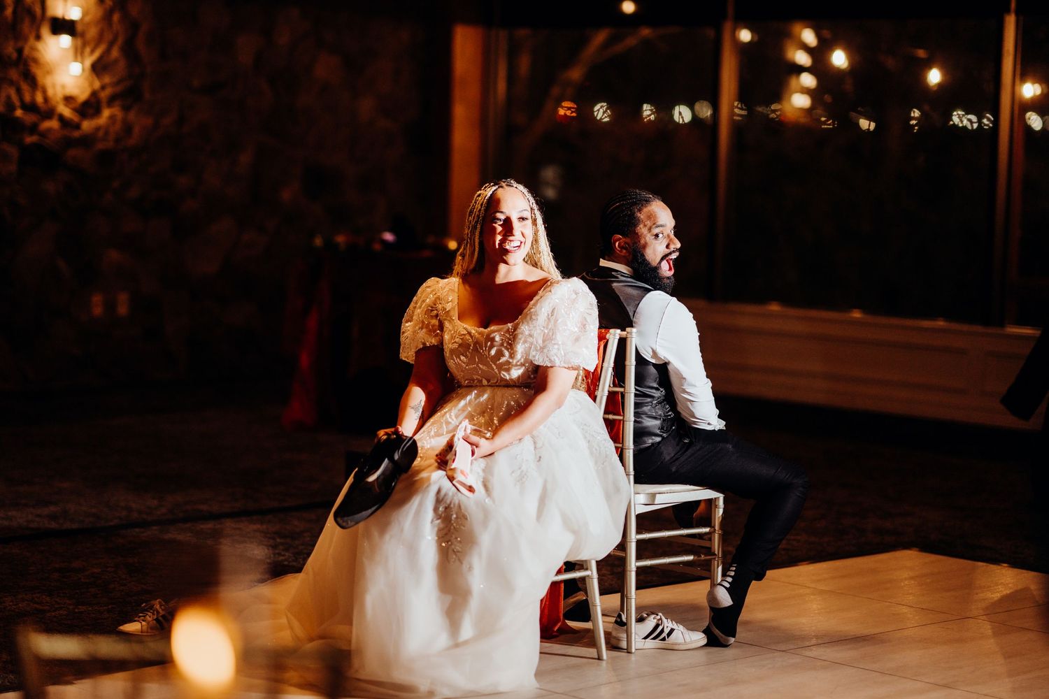 A couple plays a fun game during their wedding reception on a dimly lit dance floor.