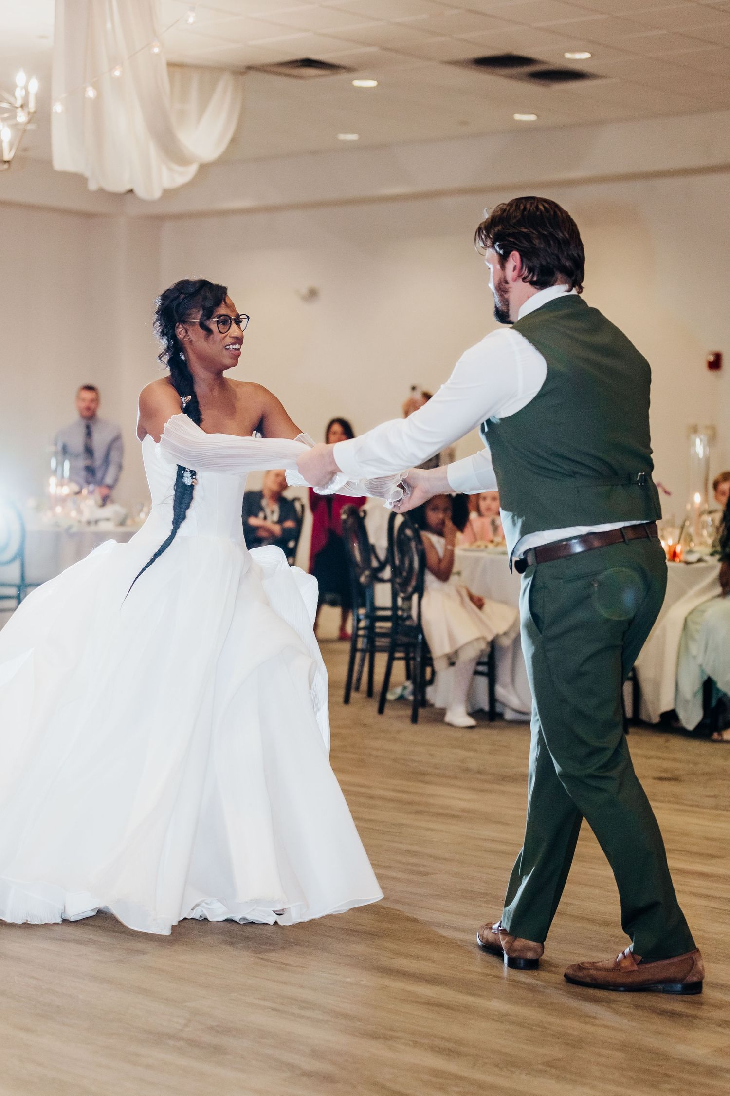 Wedding couple dances together on wooden floor during their reception celebration.