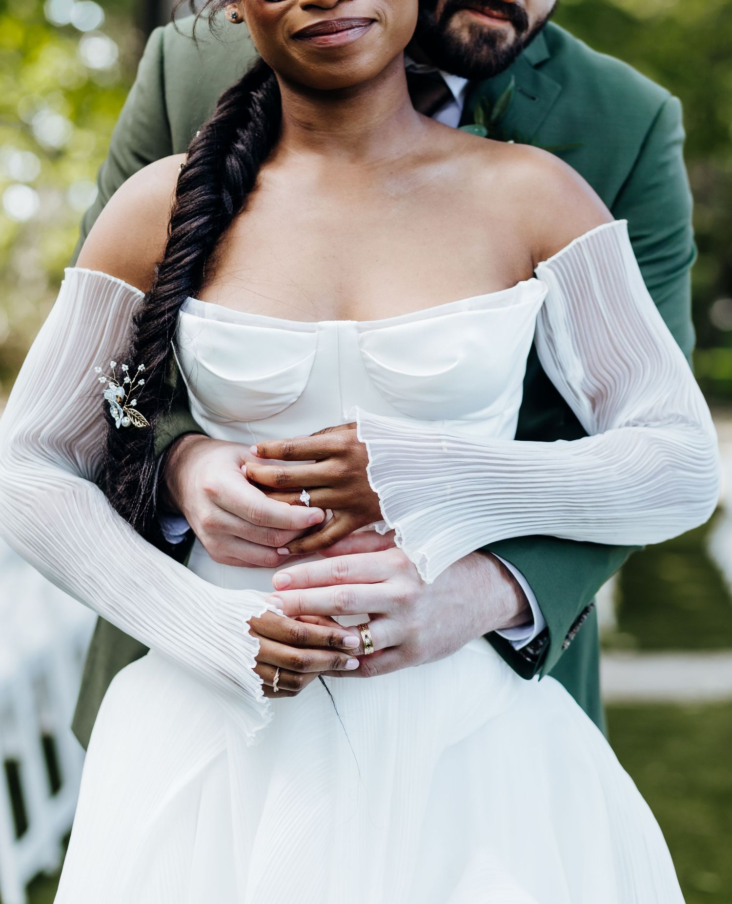 Close-up details of bride's off-shoulder white wedding gown and engagement ring.