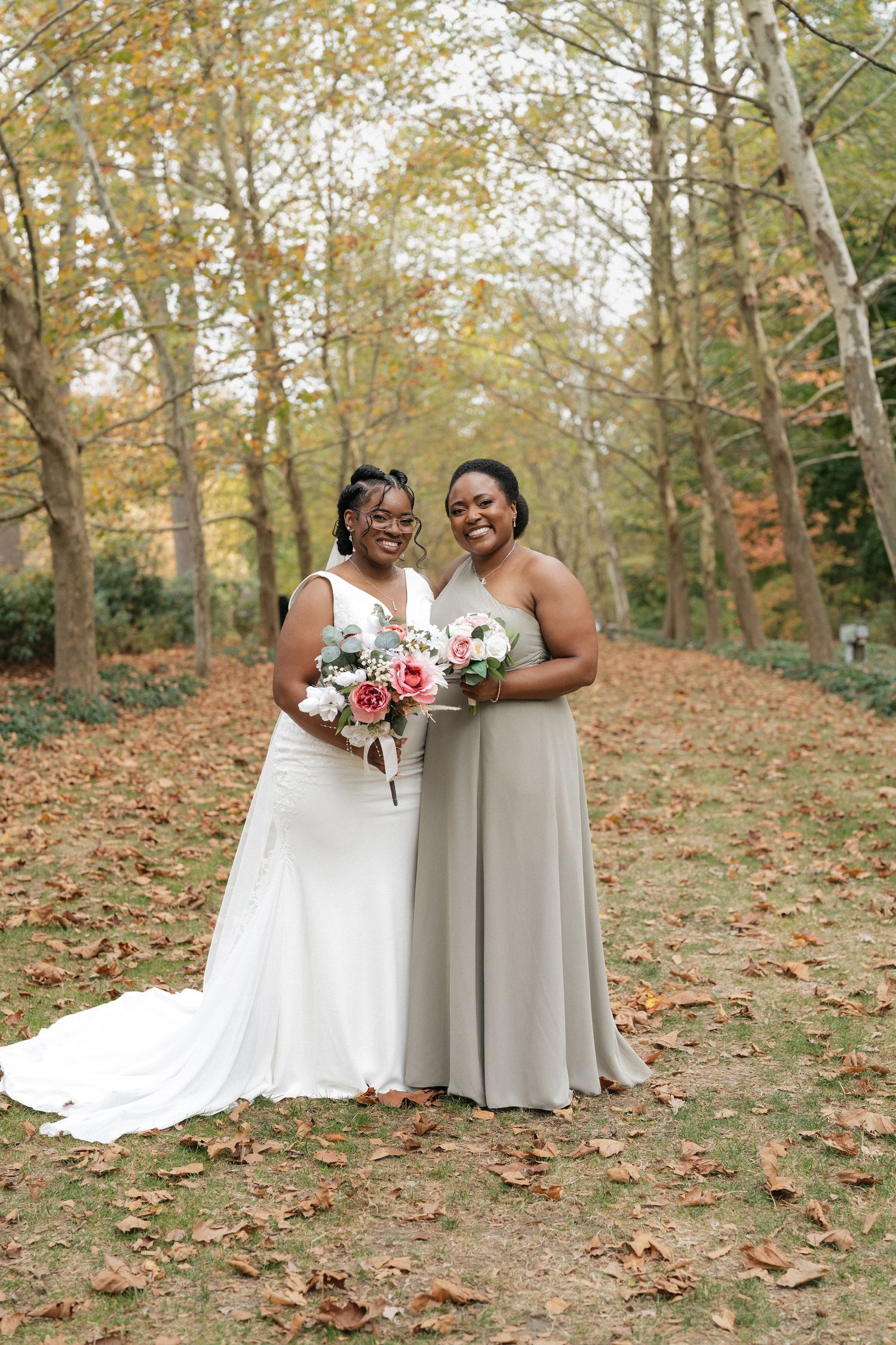 Wedding party members pose on hillside covered in autumn leaves.