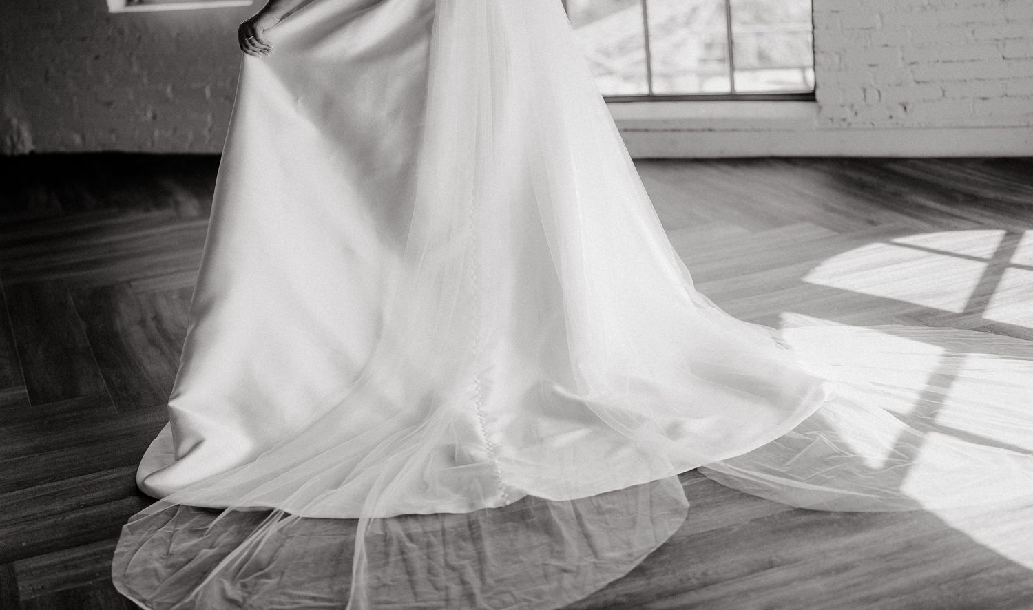Elegant white wedding dress flowing across a sunlit floor with dramatic shadows.