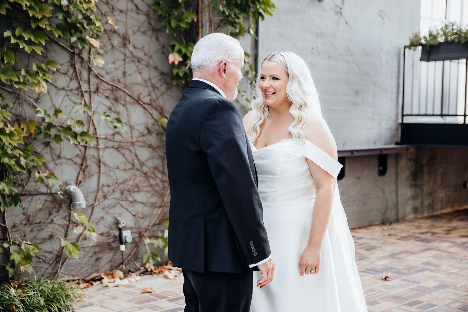 Wedding couple shares intimate moments against an ivy-covered wall outdoors.