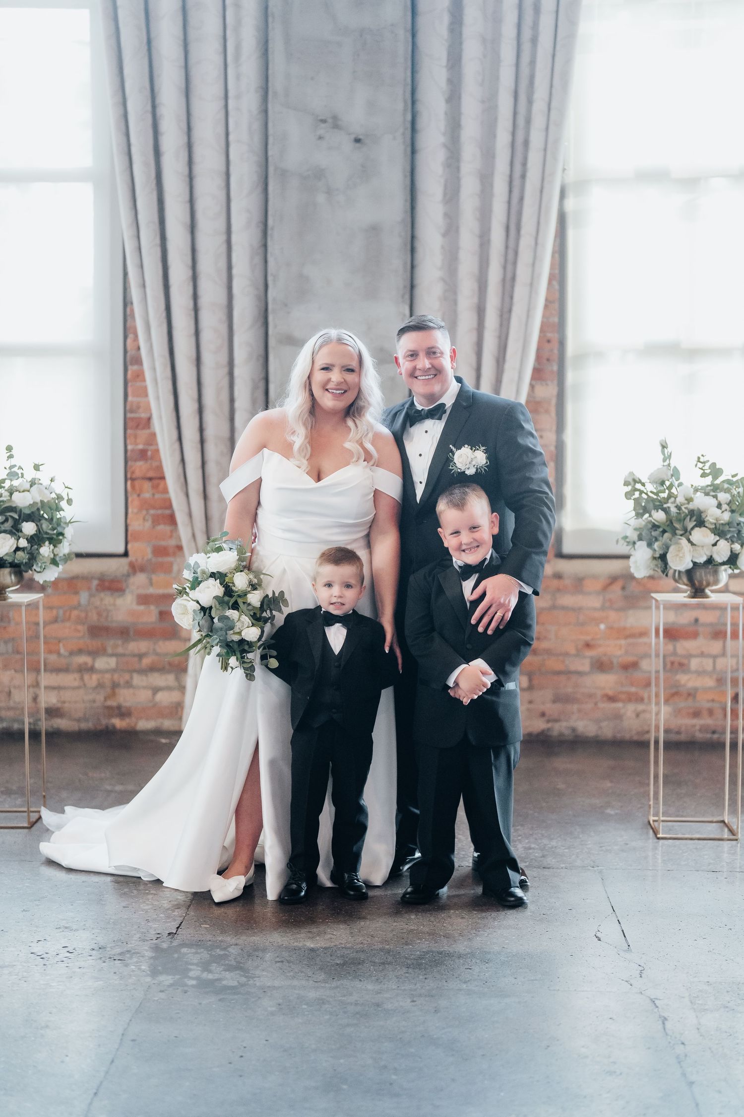 Wedding portrait in an elegant room with brick walls and grey curtains.