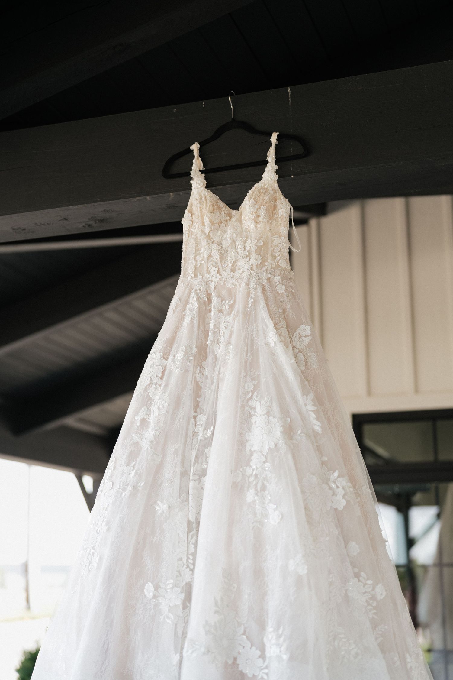Beautiful white lace wedding dresses hanging from wooden beams in preparation for the ceremony.