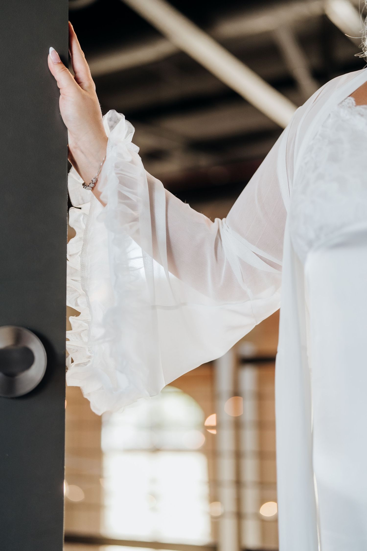 Close-up details of flowing white wedding dress fabric against an industrial backdrop.