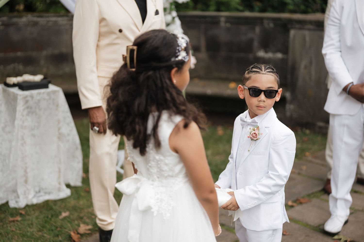 Wedding party members in white and beige attire standing together at an outdoor celebration.
