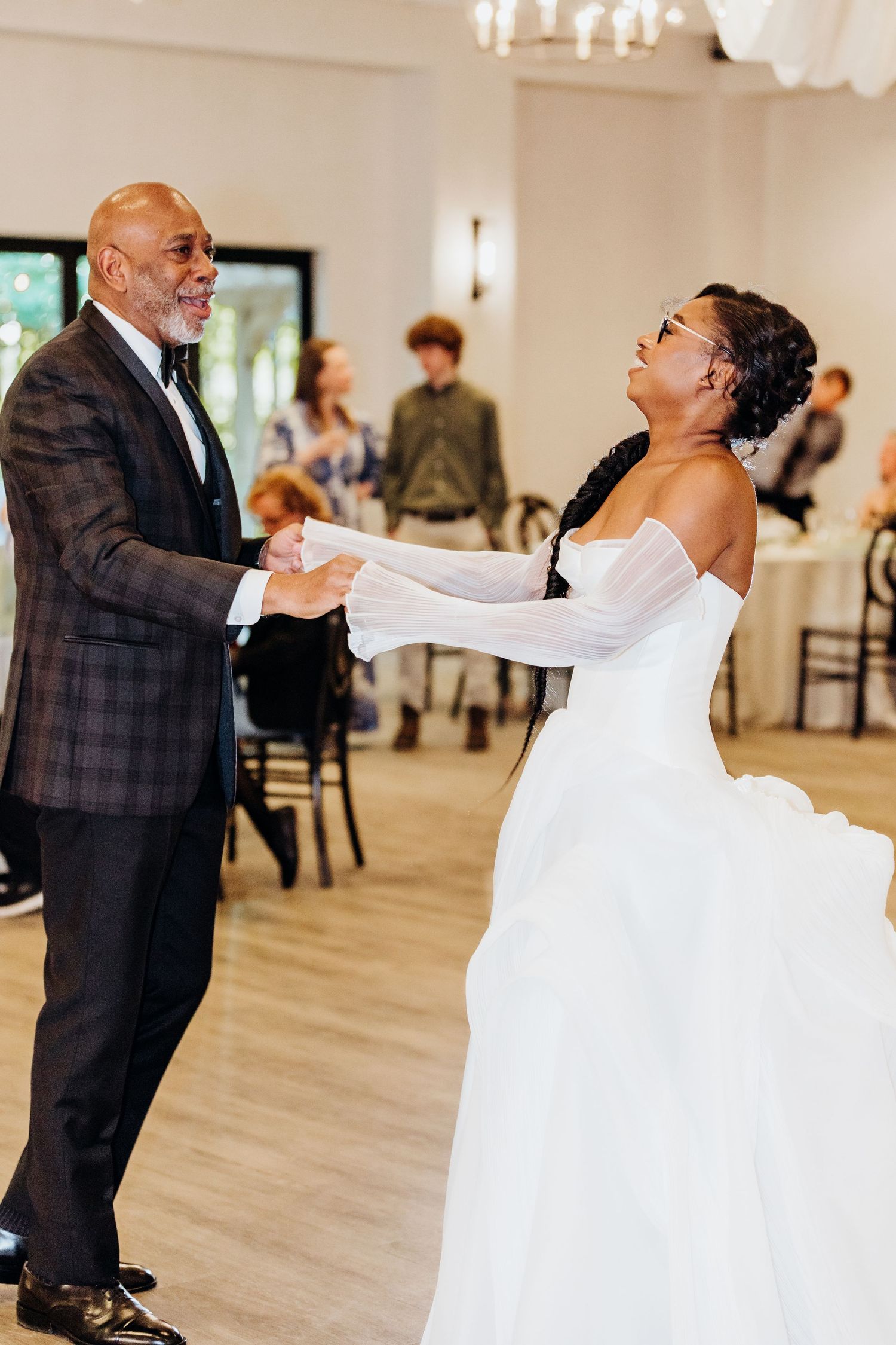 Wedding reception dance featuring flowing white dress and formal attire in elegant ballroom setting.