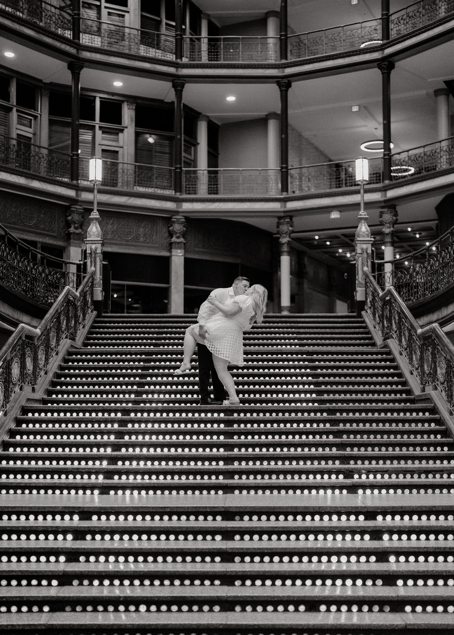 A dramatic black and white photo of a couple on a grand staircase.