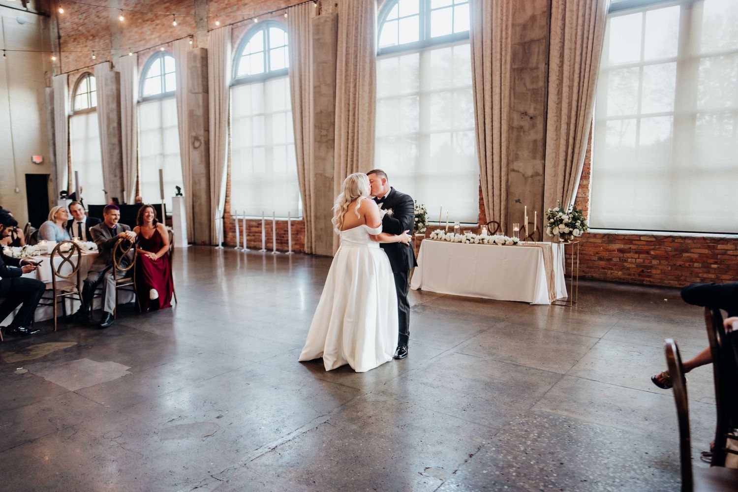 Elegant wedding ceremony setup in industrial venue with exposed brick and large windows.