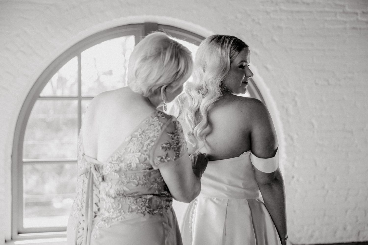 Elegant bridal portraits in a white brick room with arched windows.