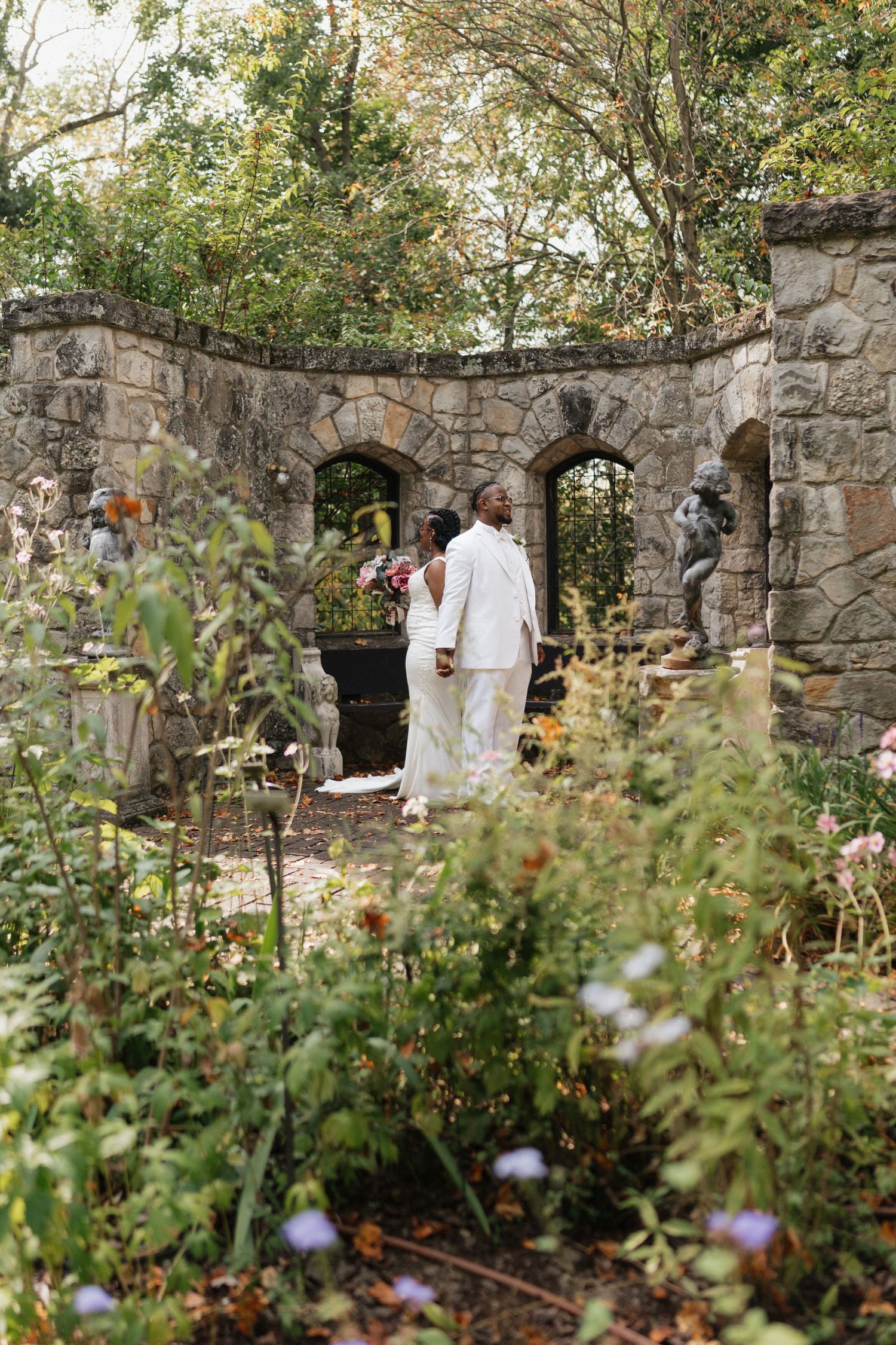 Wedding ceremony setting with stone walls and lush garden florals.