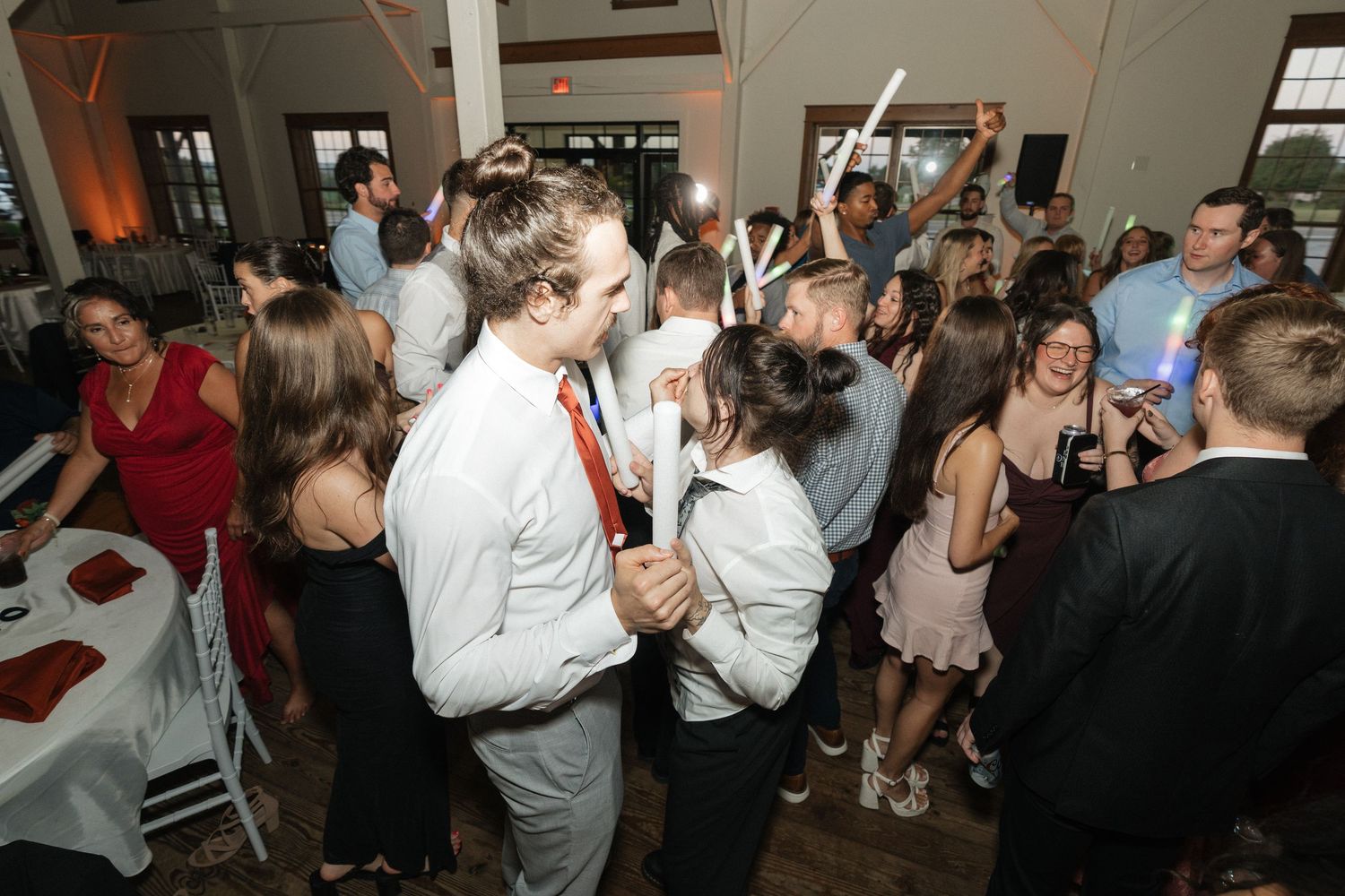 Wedding reception dance party with guests celebrating under dim lighting.