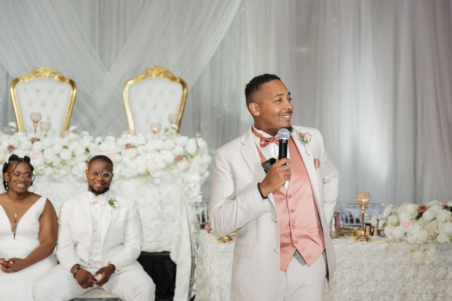 Wedding reception scene with elegant white draping and gold accents as backdrop for celebration.