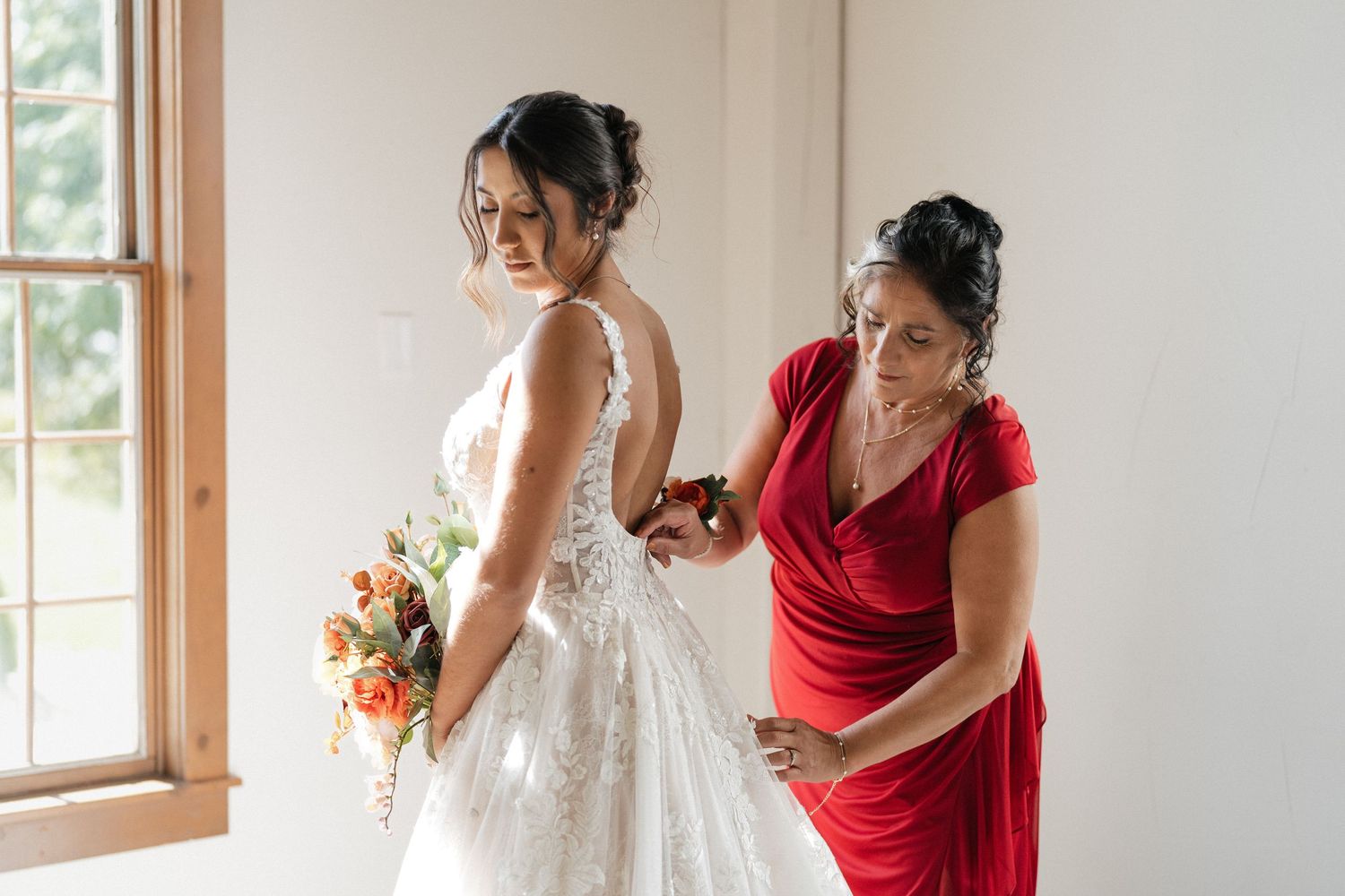 Final dress adjustments being made to white lace wedding gown before ceremony.