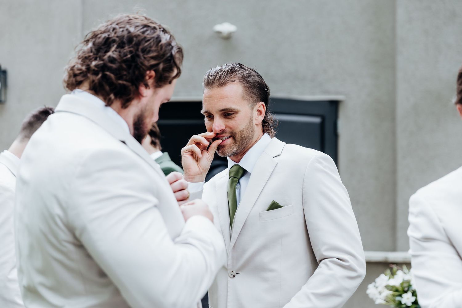 A group of groomsmen in white tuxedos share a celebratory moment together at a wedding reception.