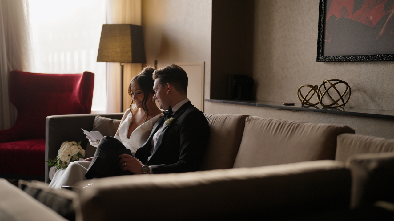 A couple sits together on a couch in a dimly lit living room with a romantic atmosphere.
