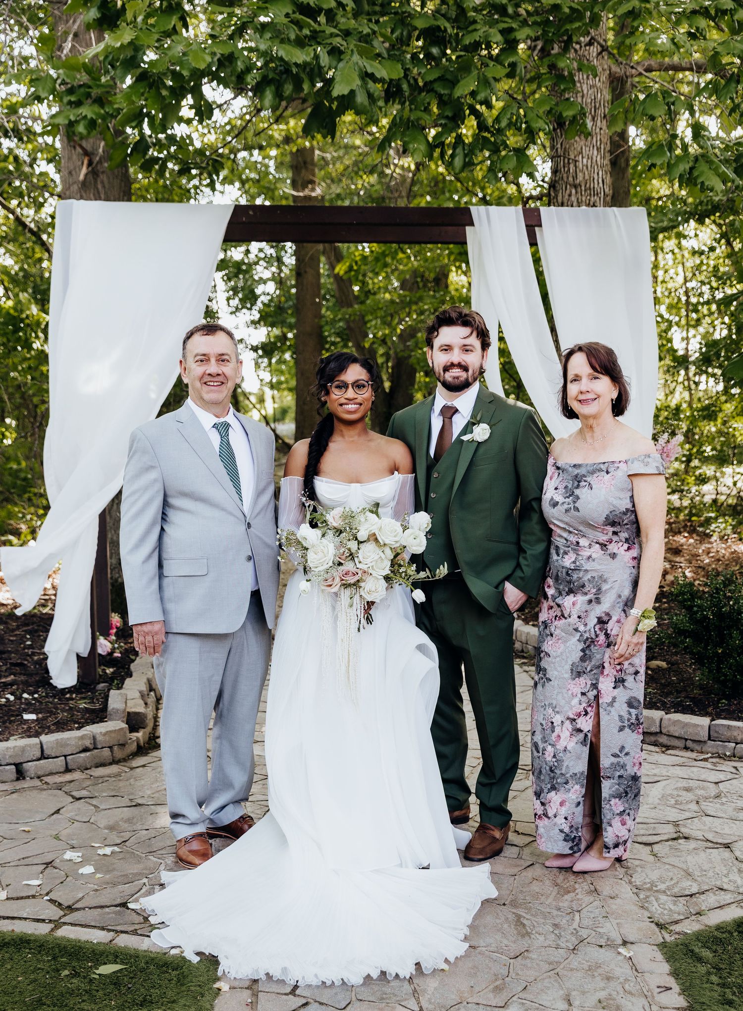 Wedding group photos being taken on a stone patio surrounded by lush greenery.