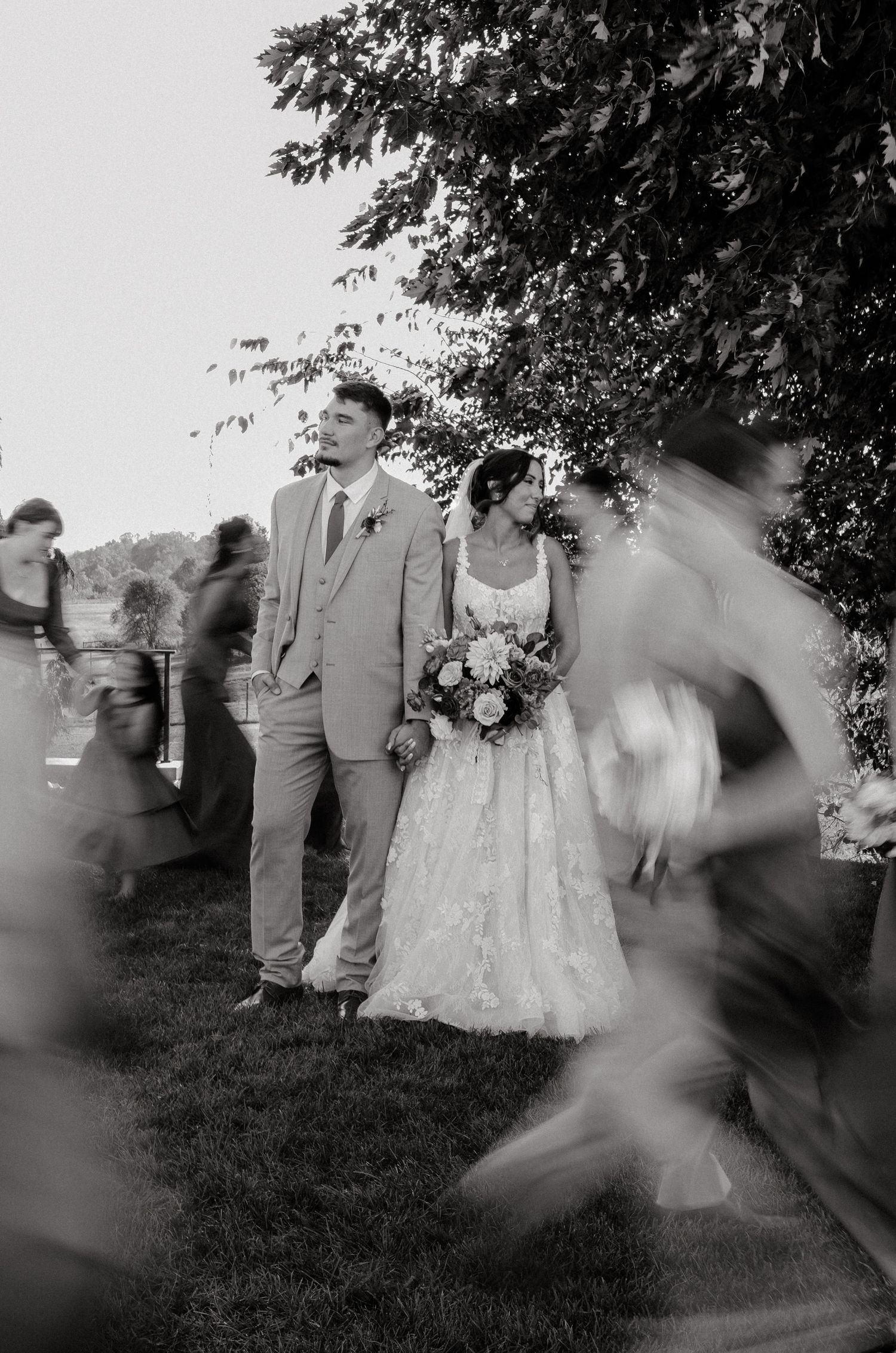 Black and white wedding photos showing movement and dancing in an outdoor garden setting.