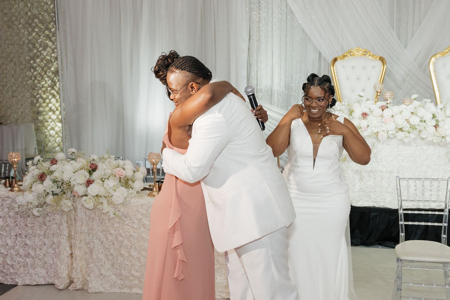 Emotional embrace during wedding reception with white and pink decor.