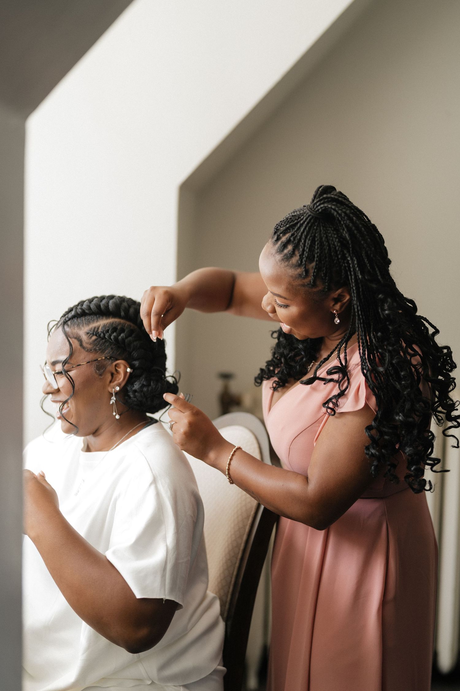 Wedding party members help style hair before the ceremony in an intimate indoor setting.