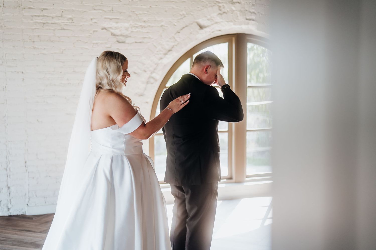 Intimate wedding moment photographed in a light-filled white brick space.