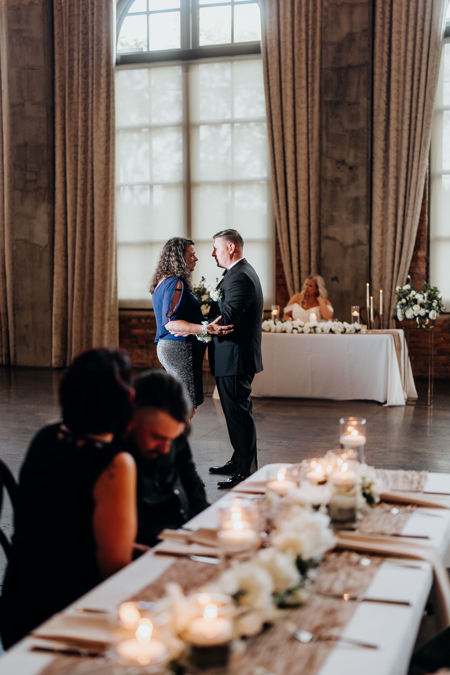 Wedding reception room with candlelit tables and floor-to-ceiling windows creating an intimate atmosphere.