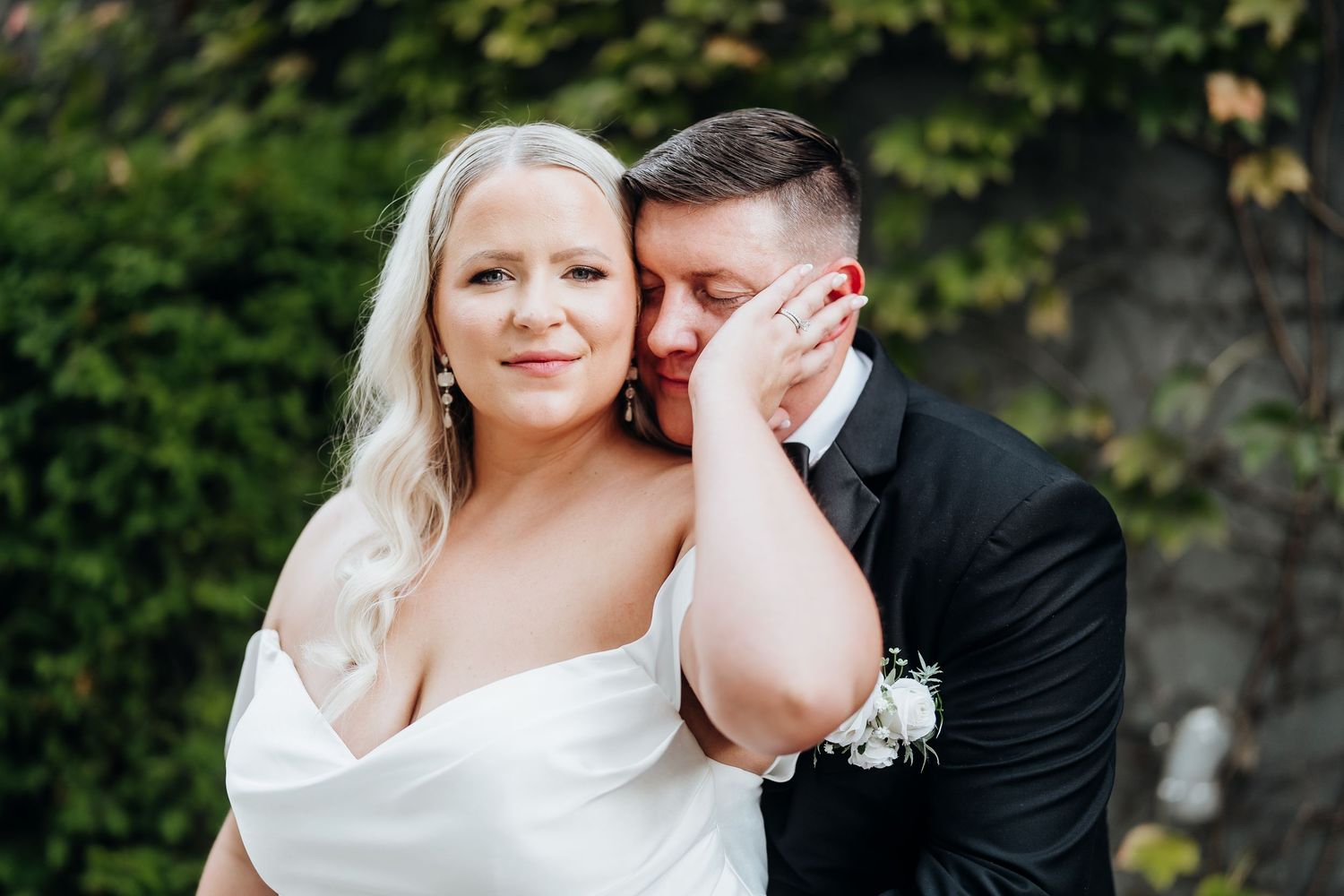 Intimate wedding portraits taken against a lush garden wall backdrop.
