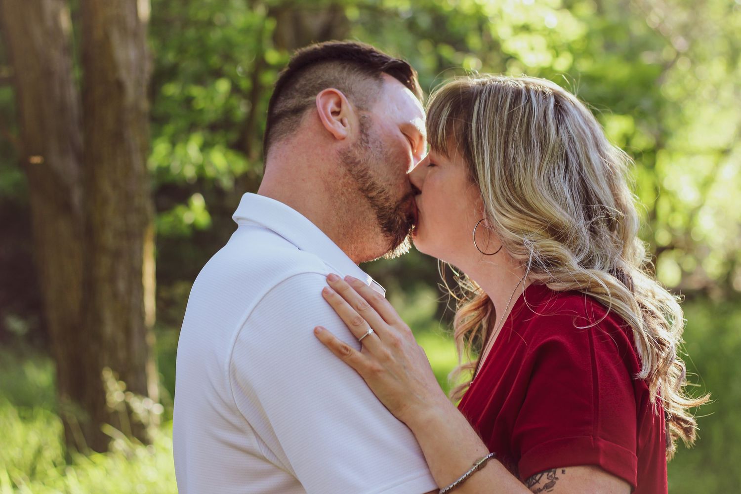 An intimate outdoor portrait showing affection between two people in coordinated red and white outfits.