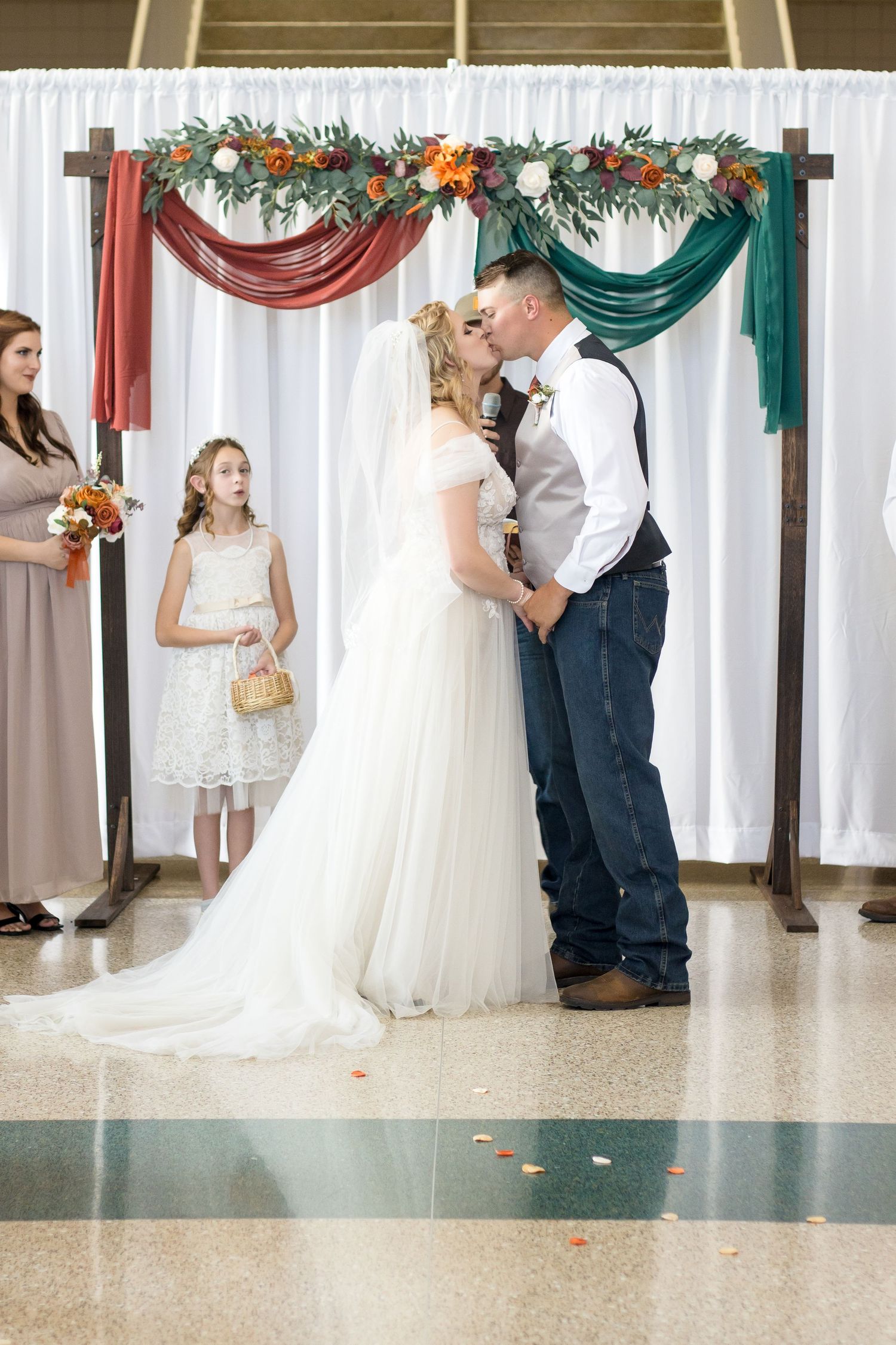 Wedding celebration in a decorated indoor venue with white curtains and greenery.