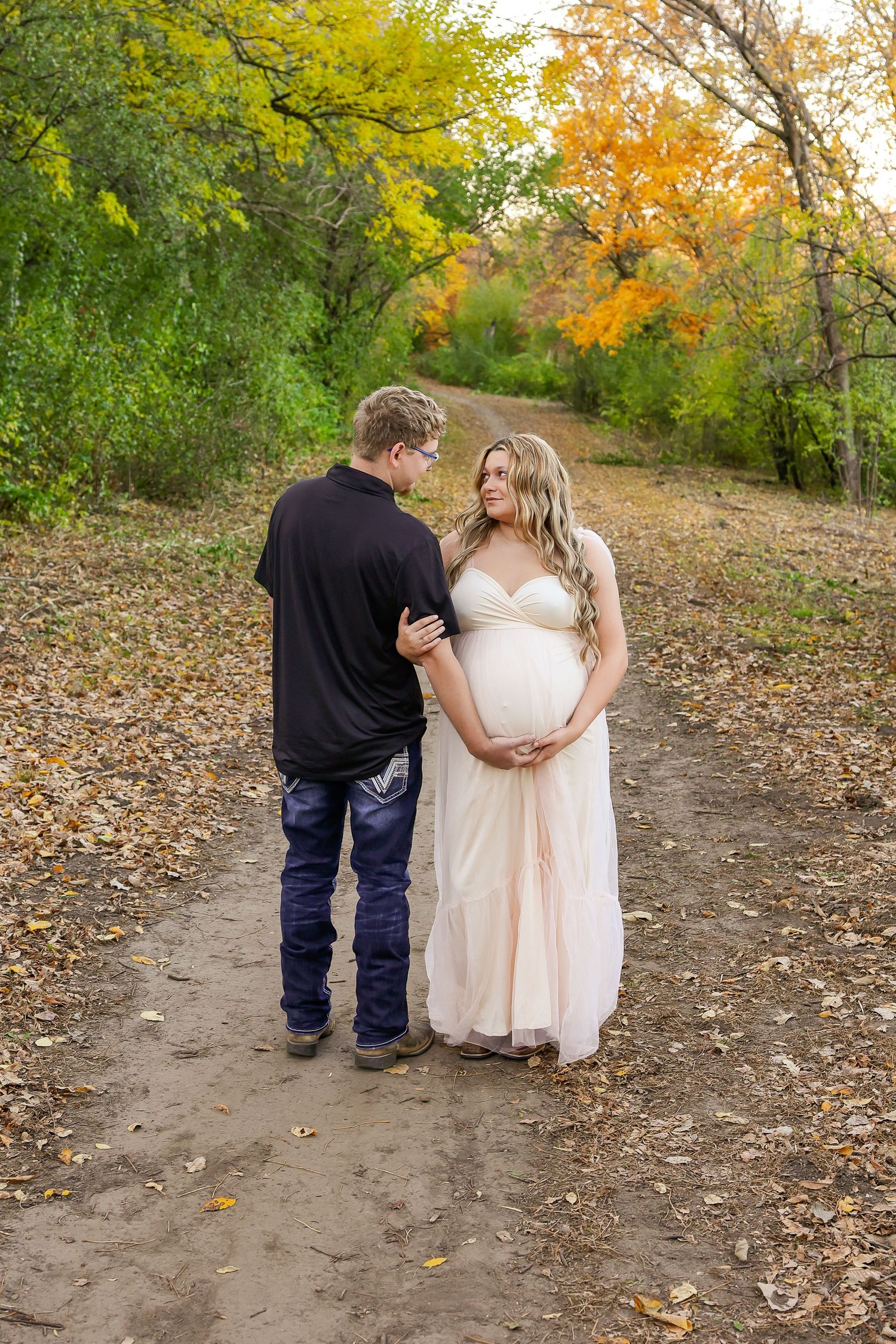 Couple walking down a winding autumn path surrounded by yellow and orange fall foliage.