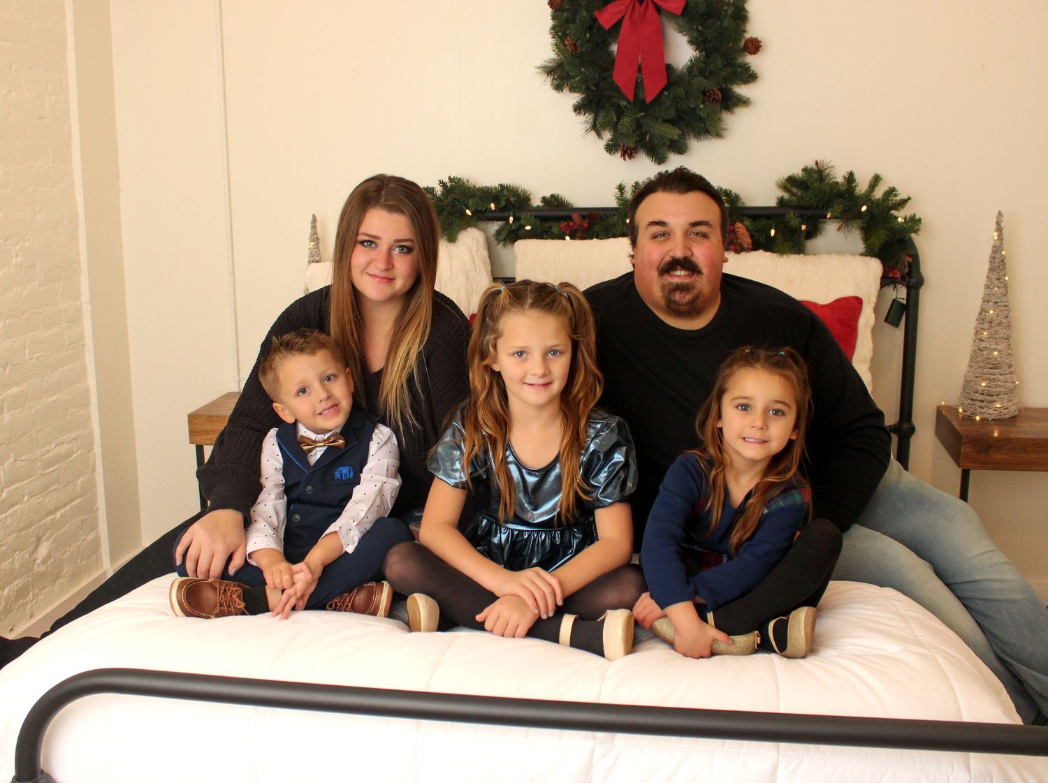 Family holiday photo session with Christmas decorations and wreaths in the background.