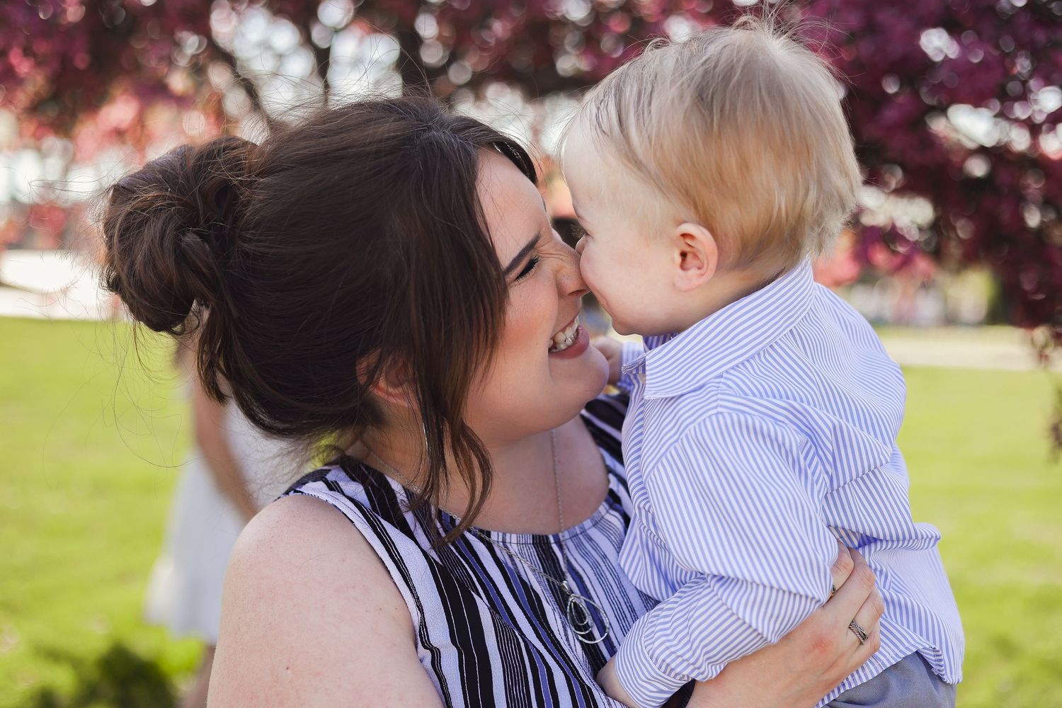 Candid moments of affection captured under blooming cherry trees on a sunny spring day.