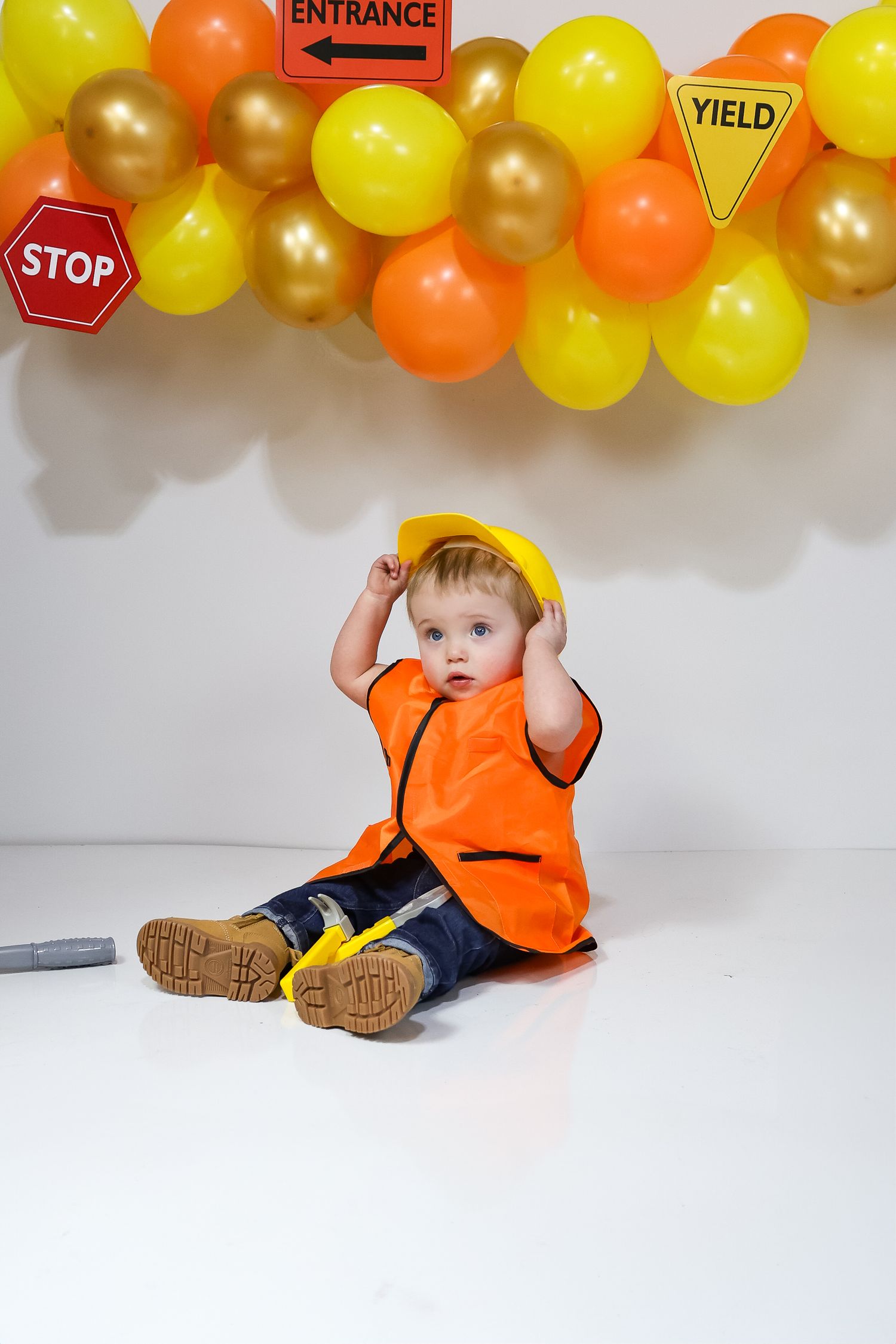 Construction themed photo setup with traffic signs and orange safety vest.
