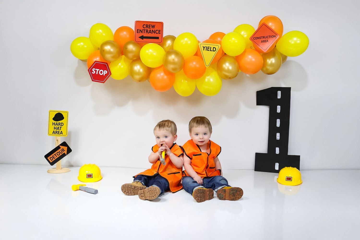 Yellow and orange balloon arch with construction signs for children's photoshoot.