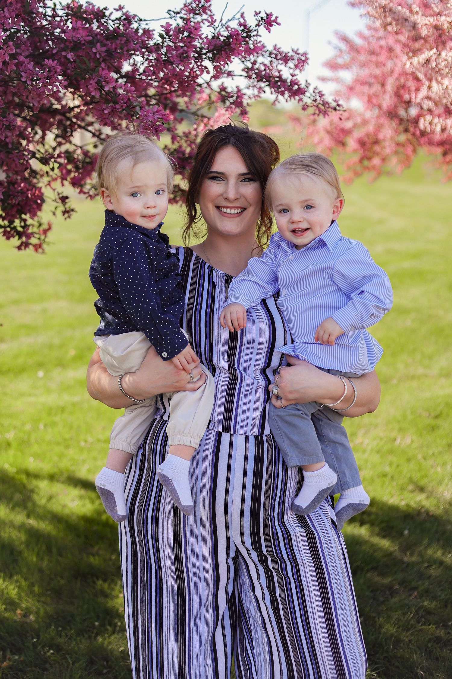 A springtime portrait under blooming pink and purple trees on a grassy lawn.