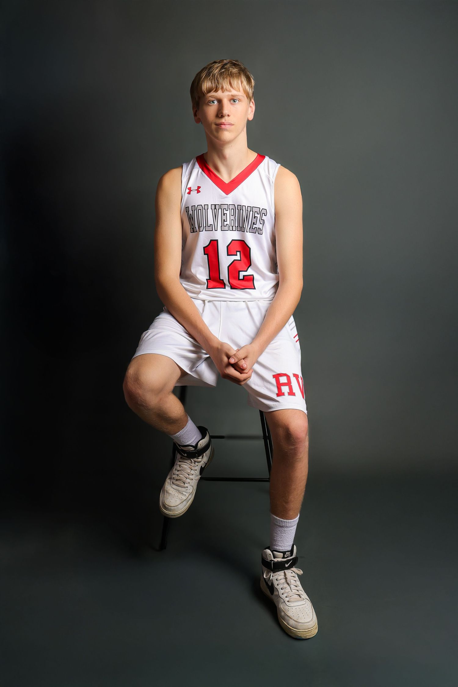 Basketball player in white jersey number 12 poses against dark backdrop in studio portraits.