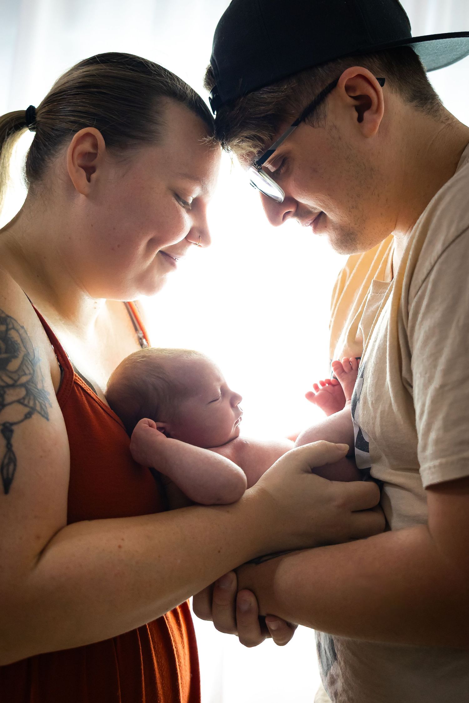 A series of tender moments between a parent and baby shown in silhouette against bright backlighting.