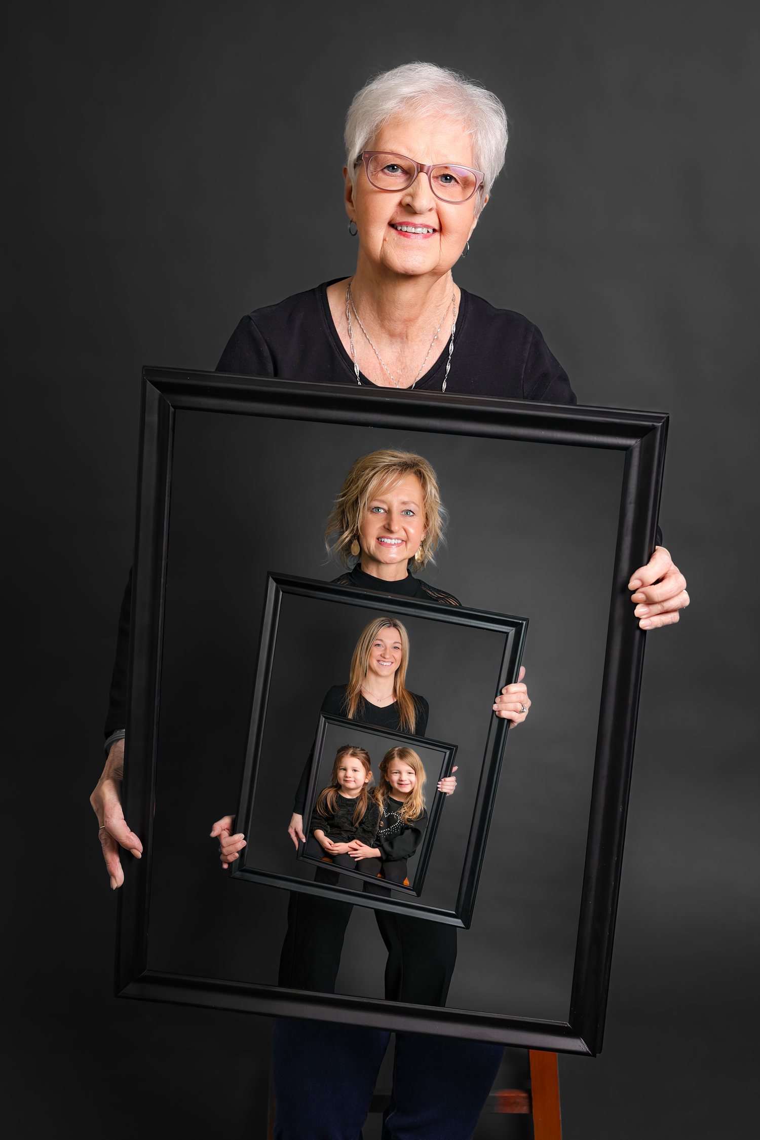 Creative generational portrait showing three nested frames with family members holding photos of the next generation.