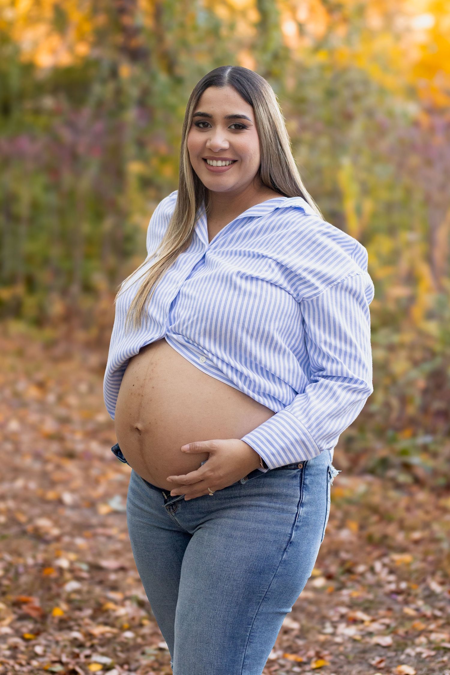 Solo maternity portraits in autumn setting with striped shirt and jeans.