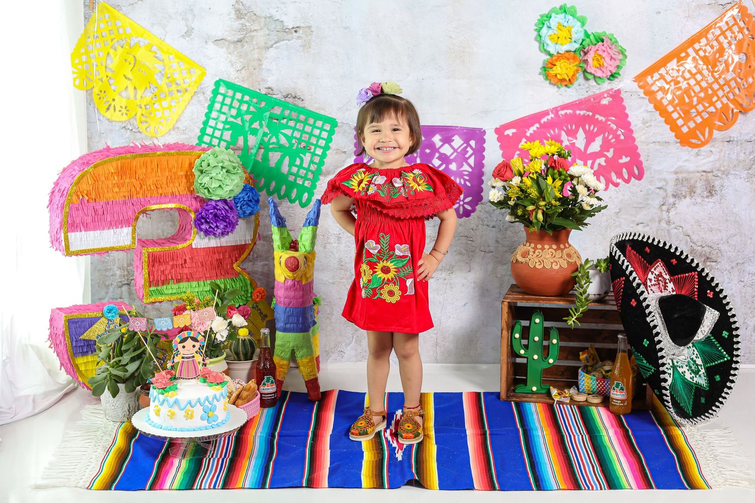 Colorful papel picado banners and Mexican decorations displayed along a striped serape blanket create a festive atmosphere.